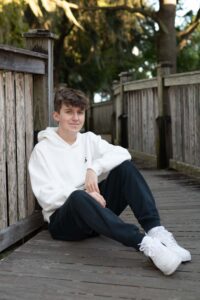 A Winter park senior boy sits at Rollins Boardwalk.