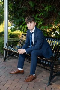 Senior boy sitting on a bench at Central Parkfor senior portraits by Winter Park senior photographer.