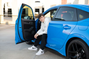 A senior boy sits in his car at Rollins College