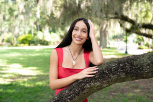 Senior girl leaning on a tree smiling during her orlando senior portrait session.
